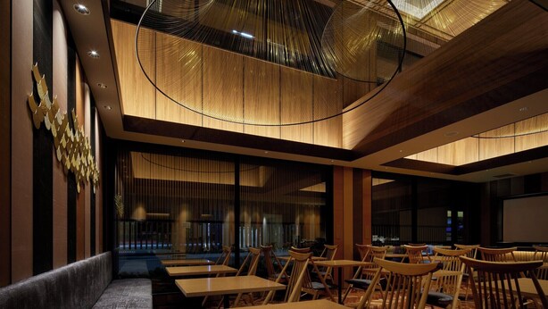 Un intérieur de restaurant moderne, avec des meubles en bois, un design de plafond original et de grandes fenêtres.
