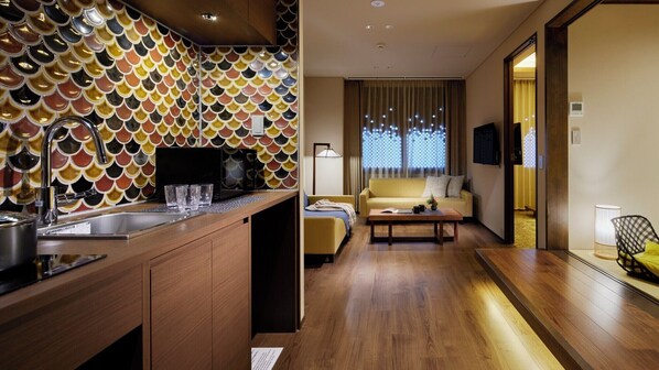 Una habitación de hotel moderna con cocina, sofá y mesa de comedor.