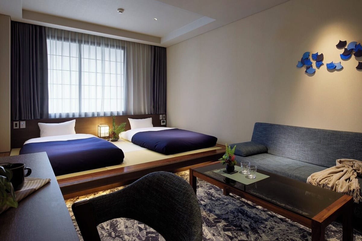 Een hotelkamer met een bed, twee nachtkastjes, een bank, een salontafel en een wandlamp.