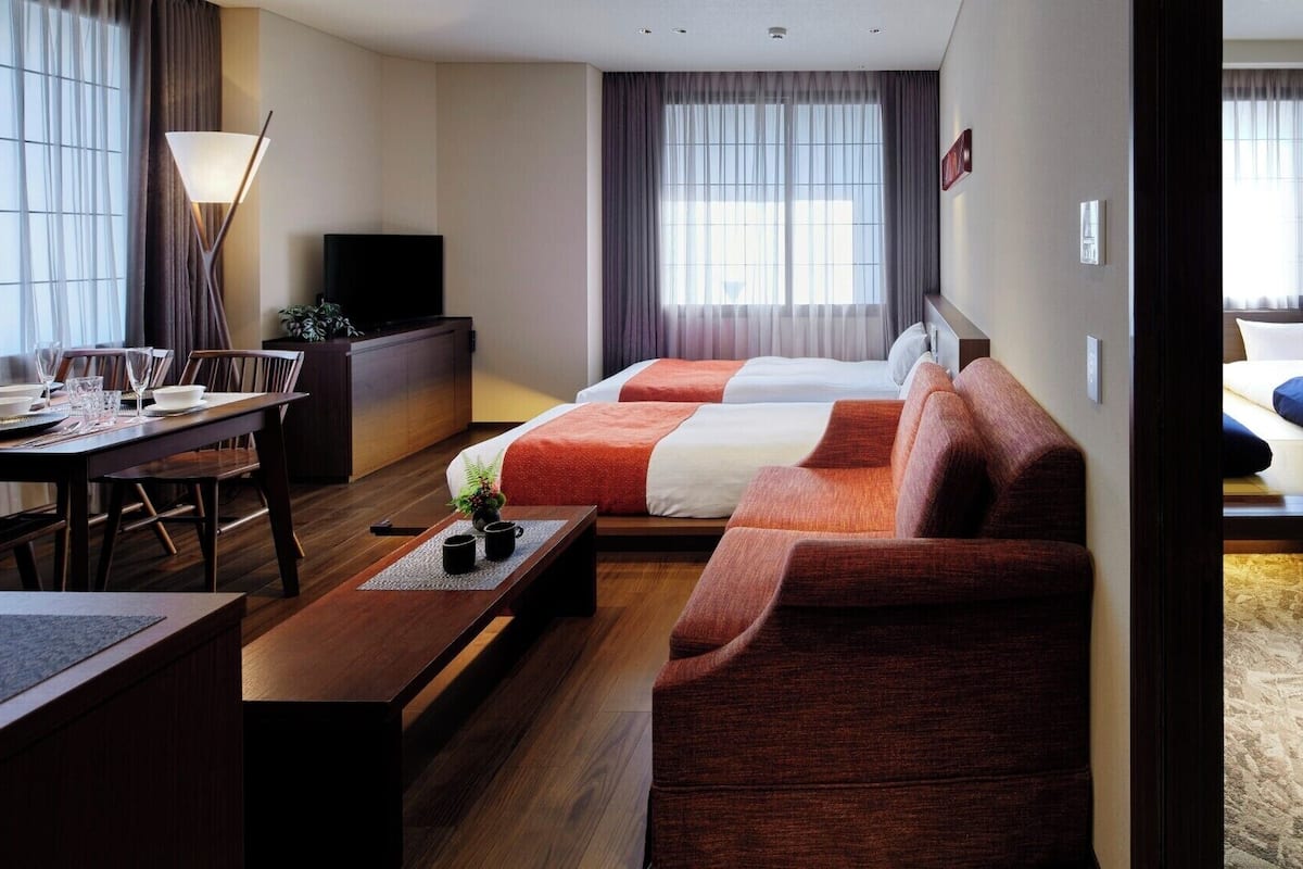 Een hotelkamer met een bank, een bed, een bureau en een eethoek.