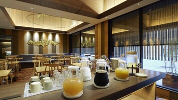 Un restaurante moderno con muebles de madera, diversas bebidas y vistas al exterior.