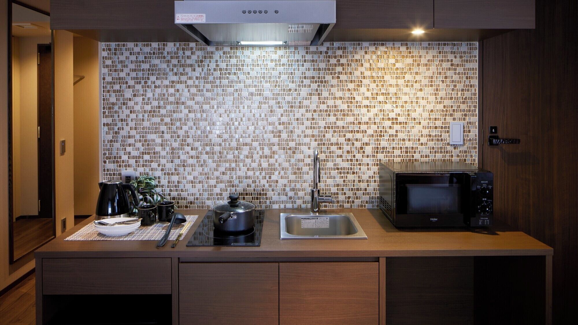 Een moderne keuken met een betegelde spatwand, een magnetron, een spoelbak en een fornuis.