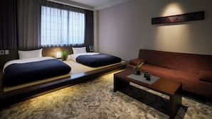 Une chambre d’hôtel avec deux lits, un canapé, une table basse et un élément décoratif mural.