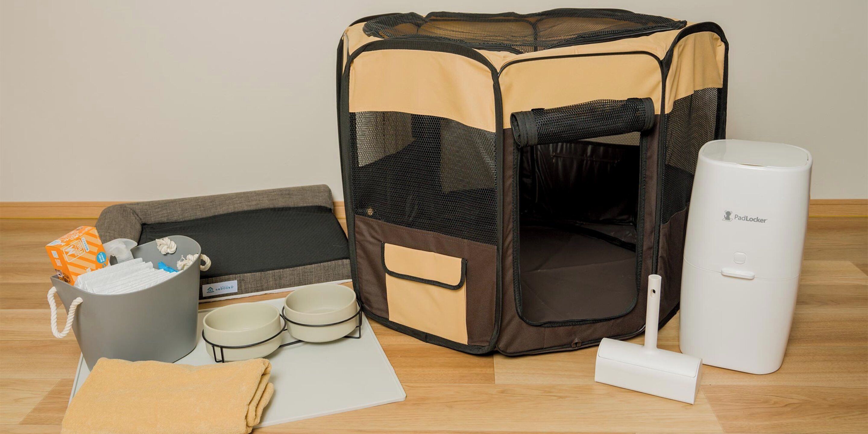 A pet bed, a waste bin, a water bottle, and a white device on a wooden floor.