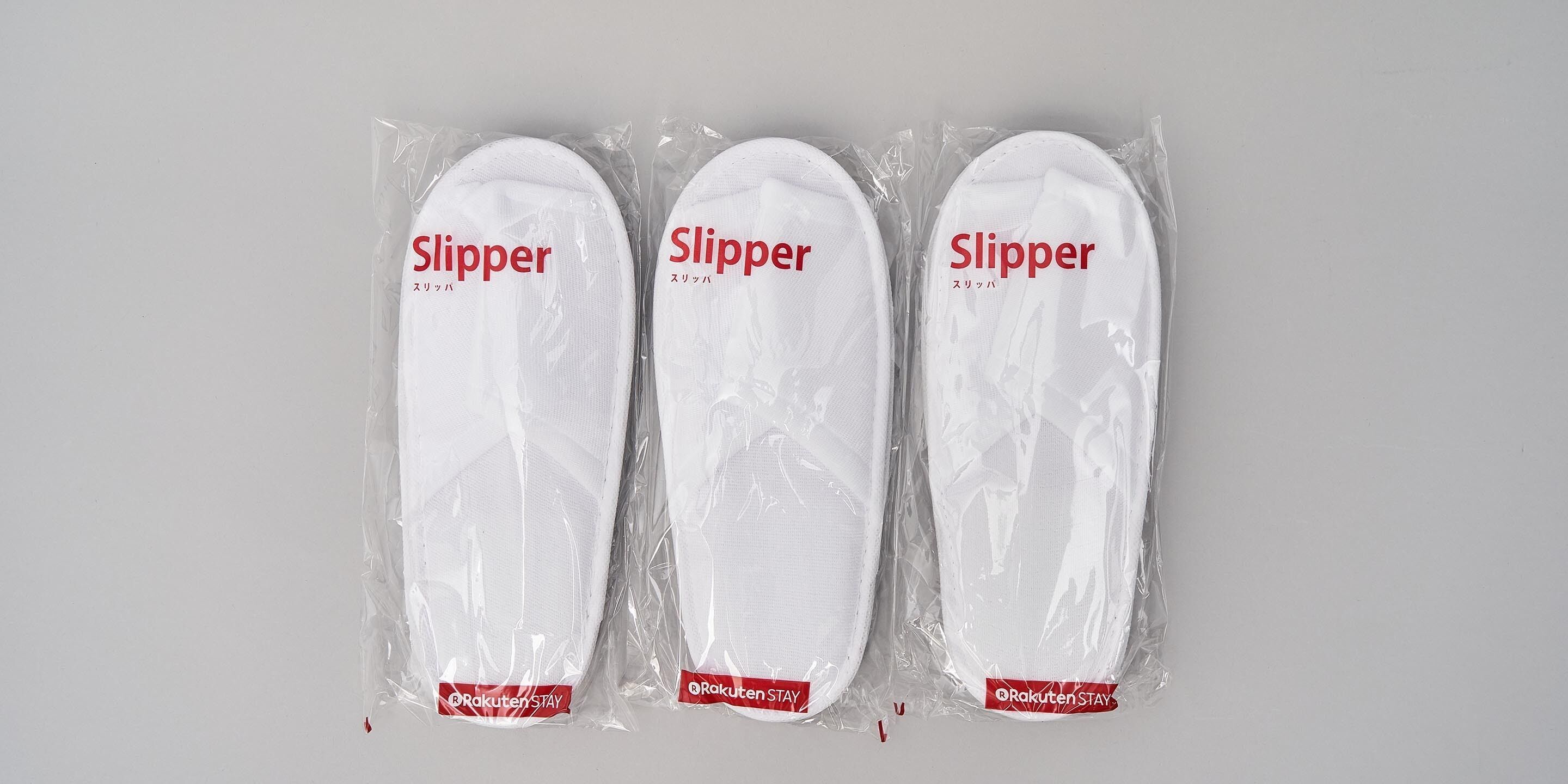 Three pairs of slippers in plastic packaging with the label "Slipper" and "Rakuten Stay".