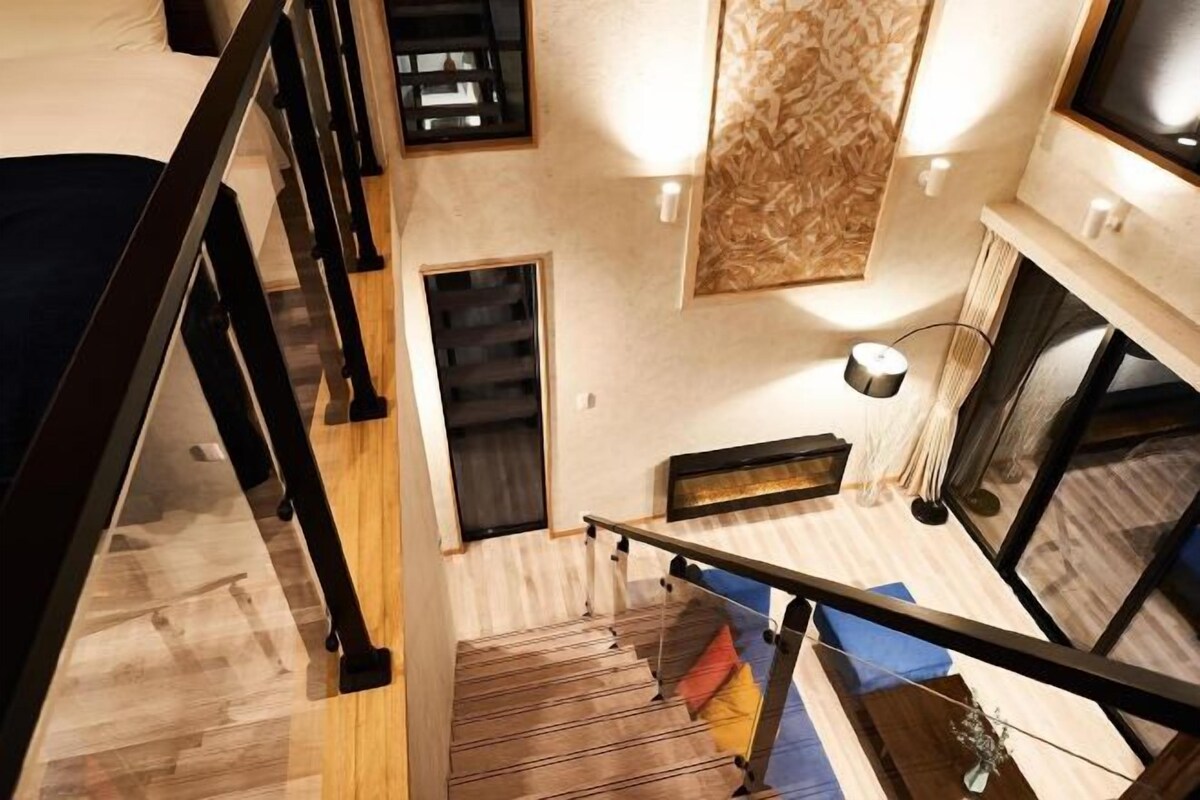 A modern interior with a staircase leading to a lower level, a fireplace, and a view of the outside.