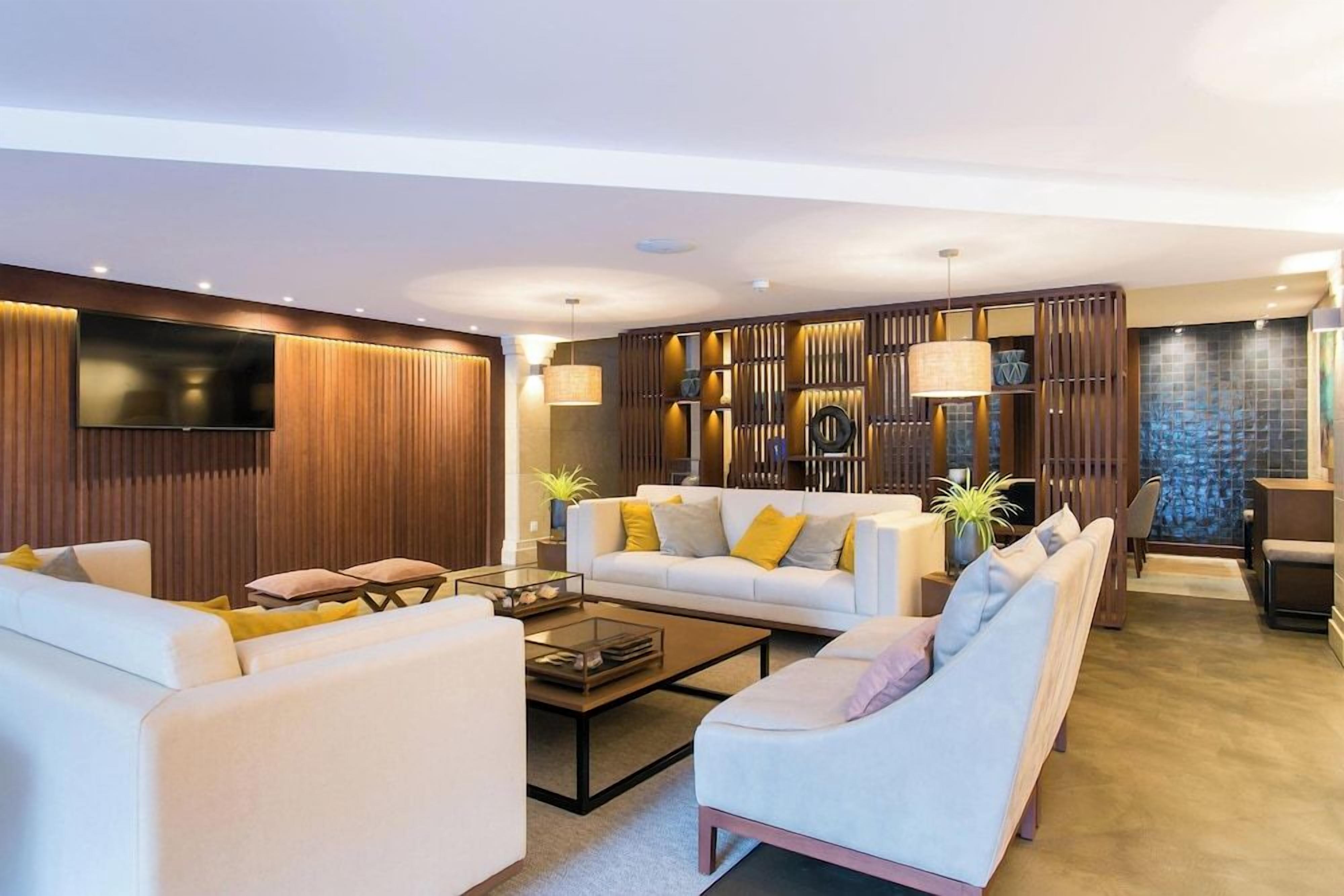 A modern living room with a sofa set, a coffee table, and a TV mounted on the wall.