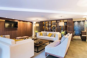 A modern living room with a sofa set, a coffee table, and a TV mounted on the wall. - Four Points By Sheraton Sesimbra (Sesimbra)