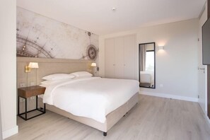 A modern bedroom with a large bed, bedside lamps, a marble wall, and a wardrobe. - Four Points By Sheraton Sesimbra (Sesimbra)