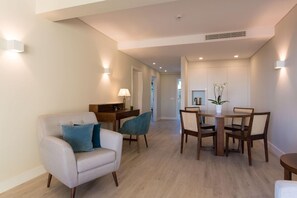 A modern living room with a sofa, dining table, chairs, and a lamp. - Four Points By Sheraton Sesimbra (Sesimbra)