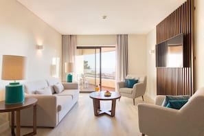 A modern hotel room with a sofa, armchairs, a coffee table, a TV, and a balcony with a view. - Four Points By Sheraton Sesimbra (Sesimbra)