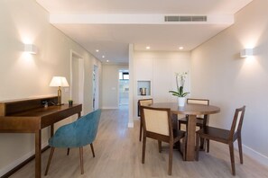 A modern dining area with a wooden table and chairs, a blue chair, and a potted plant. - Four Points By Sheraton Sesimbra (Sesimbra)