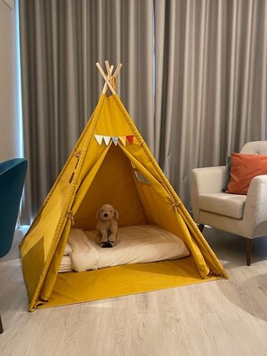A yellow tent-like structure with a dog inside, set against a backdrop of curtains and a chair. - Four Points By Sheraton Sesimbra (Sesimbra)