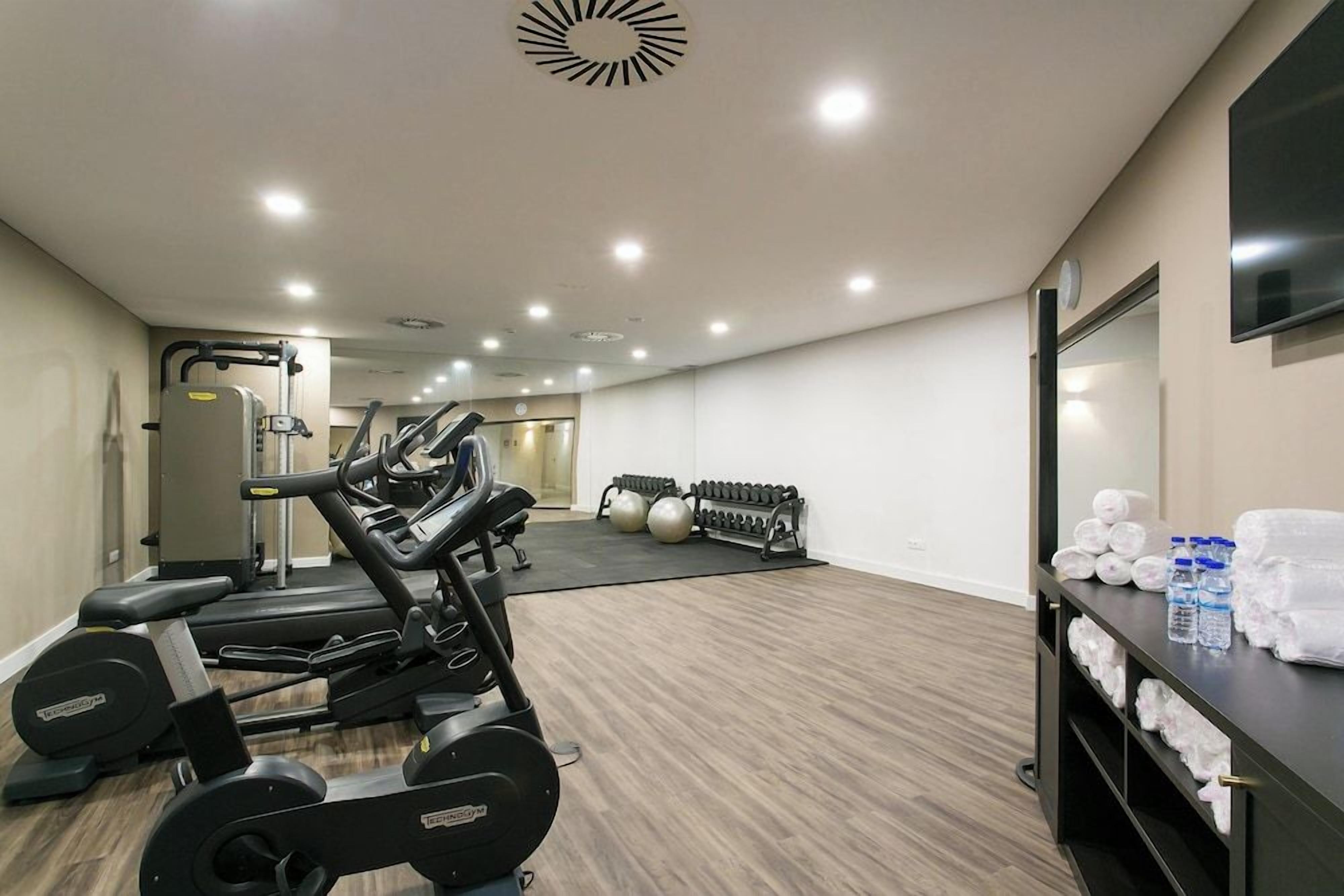 A gym with cardio machines, free weights, and exercise balls.