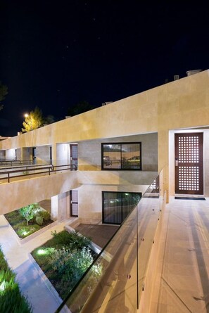A modern building with a courtyard, outdoor seating, and a glass door entrance.