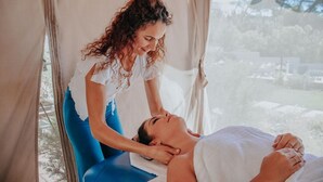 Eine Person erhält eine Massage in einem Zimmer mit Blick auf Bäume und ein Gebäude.
