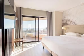 Ett modernt hotellrum med en stor säng, utsikt genom en skjutdörr i glas och en balkong.