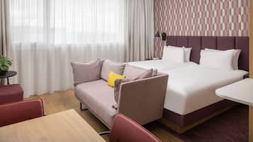 Una habitación de hotel con cama, sofá, una mesita y una lámpara.