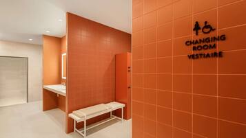 A changing room with orange walls, a bench, and a sign indicating it is a changing room for Vestiaire.