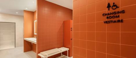 Un vestiaire aux murs orange, avec un banc et un panneau indiquant qu’il s’agit d’un vestiaire réservé à Vestiaire.
