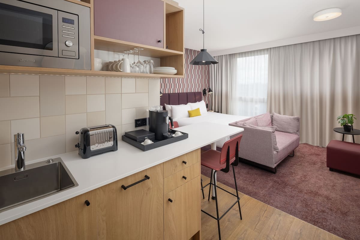 Une cuisine moderne équipée d’un four à micro-ondes, d’un grille-pain et d’une machine à café, le tout posé sur le plan de travail. On y trouve également un coin repas avec un canapé et des fauteuils.