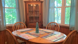Ein Esszimmer mit Holztisch, Stühlen, einer Chandelieber und einem Schrank mit Glastüren.