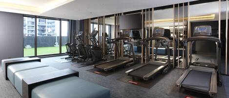 A gym with treadmills, elliptical machines, and a bench.