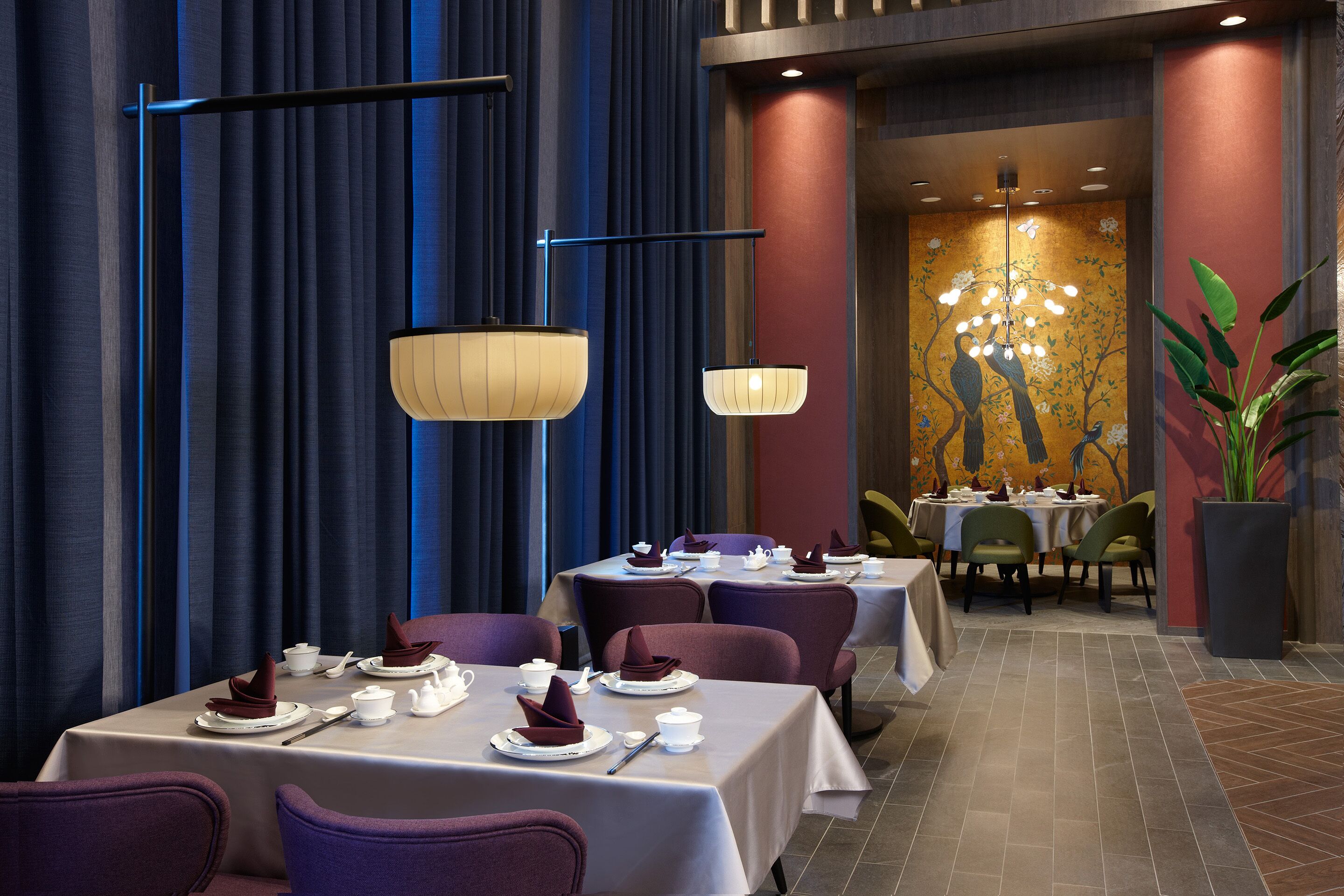 A restaurant with tables set for dining, featuring a modern chandelier and a mural on the wall.