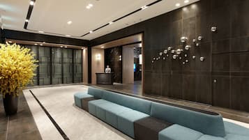 A modern lobby with a seating area, a reception desk, and a decorative wall with spherical elements.
