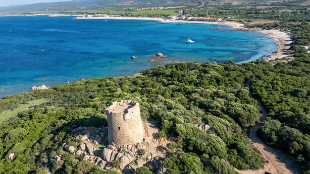 A coastal landscape with a prominent tower structure surrounded by dense greenery.