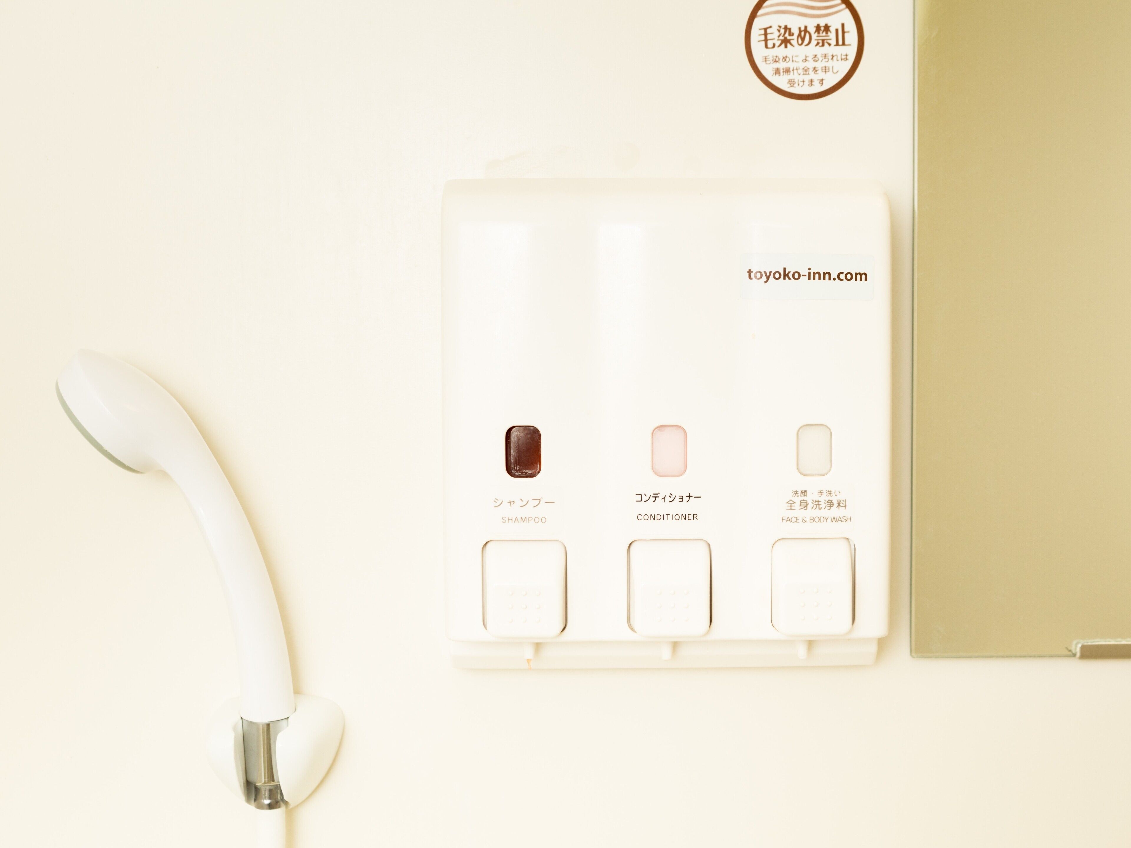 A bathroom with a white toilet, a white sink, and a white shower. There is a white towel hanging on the wall.