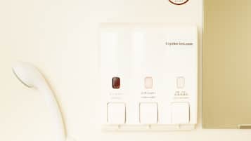 Une salle de bain avec des toilettes blanches, un lavabo blanc et une douche blanche. Une serviette blanche est accrochée au mur.