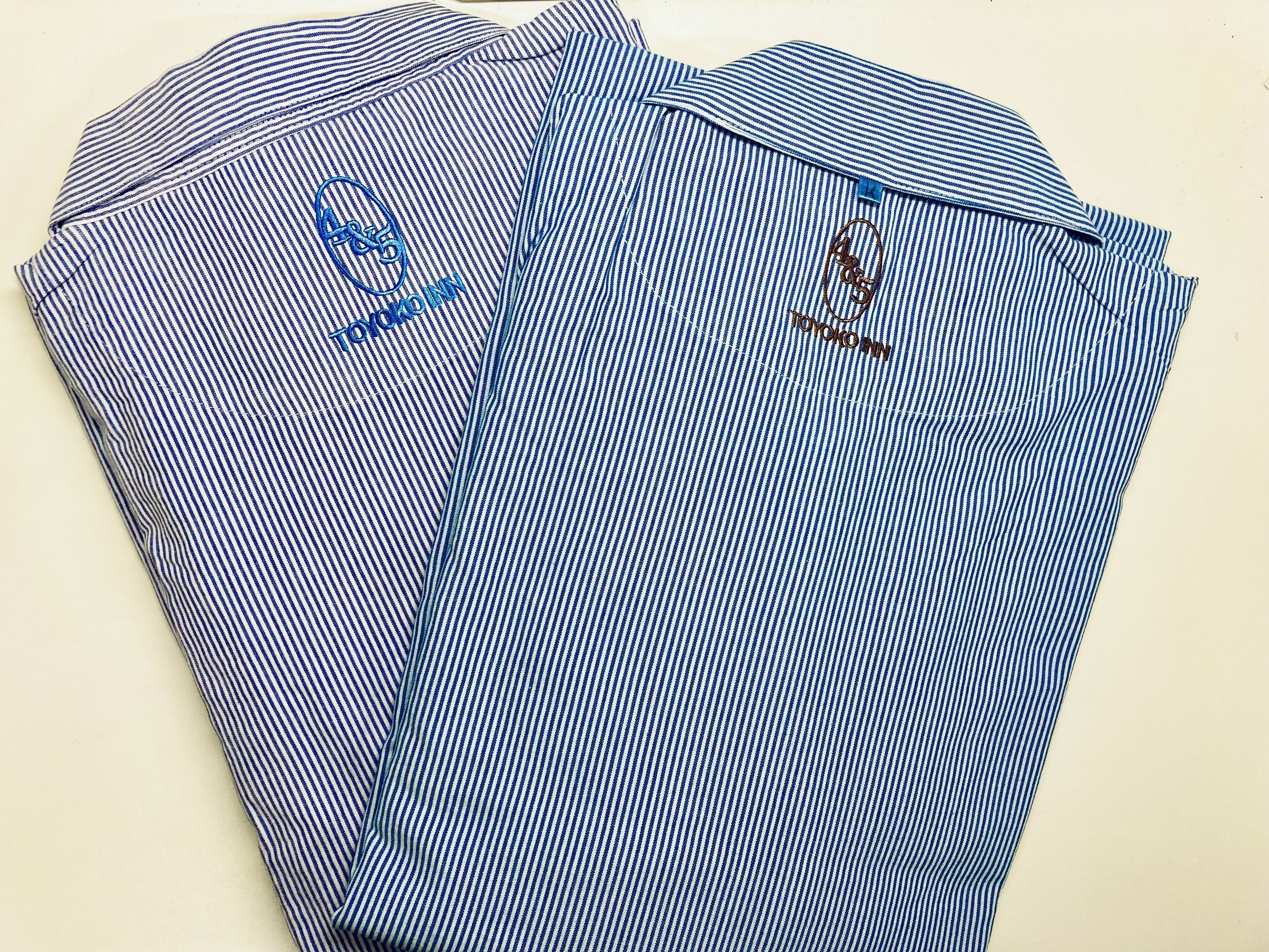 A blue and white striped shirt with embroidered logos.