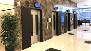 Un vestíbulo moderno con paredes de mármol, ascensores y una mesa de recepción.