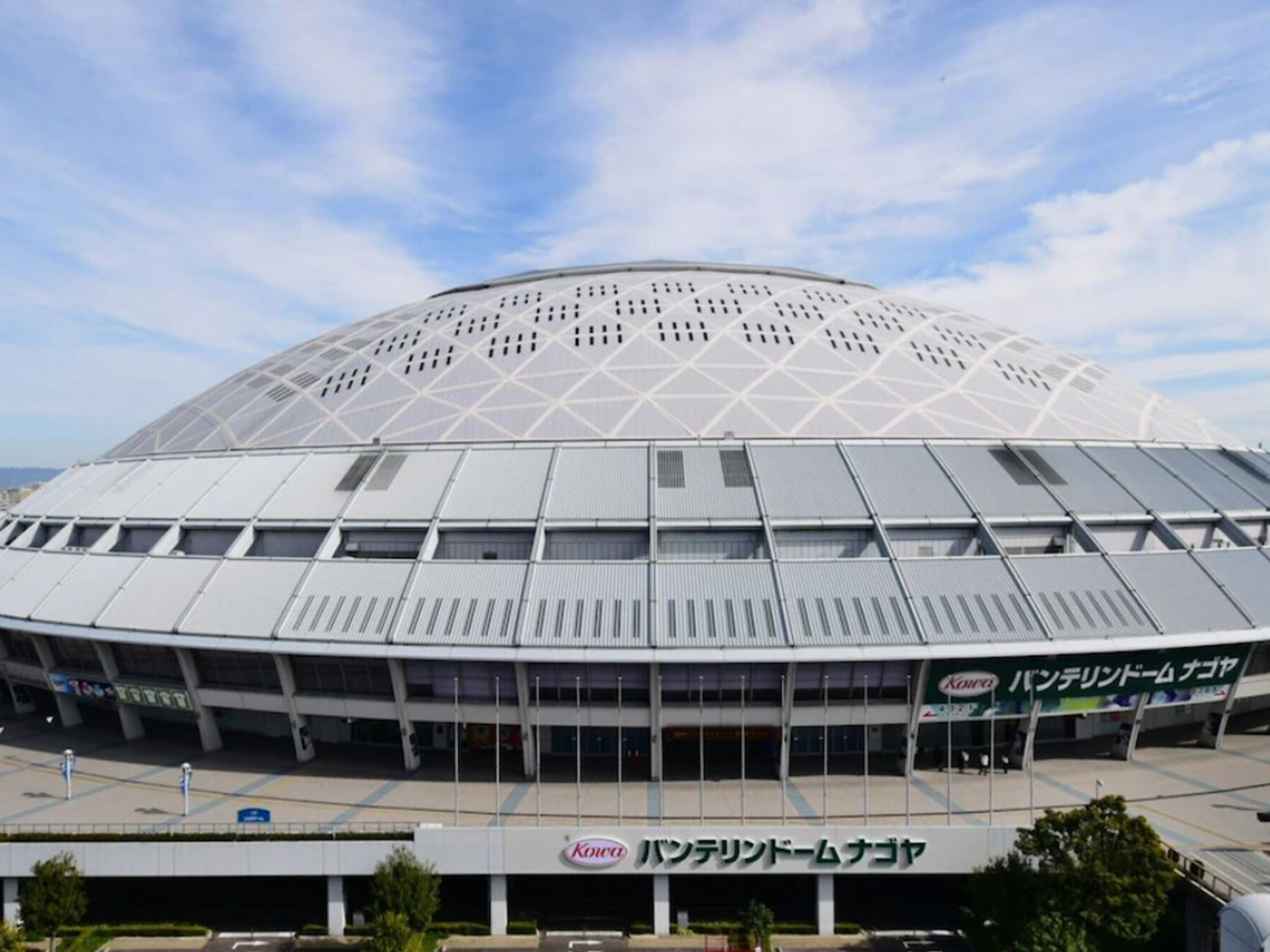 A large, modern stadium with a dome roof and a commercial building labeled "Kowa Panterland Nagoa" in front.
