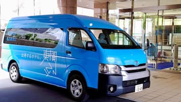 A blue van parked in front of a building with large windows and a tiled floor.