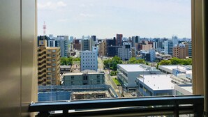 Un paisaje urbano a través de una ventana, con varios edificios altos, cielo despejado y una obra en construcción visible en primer plano.