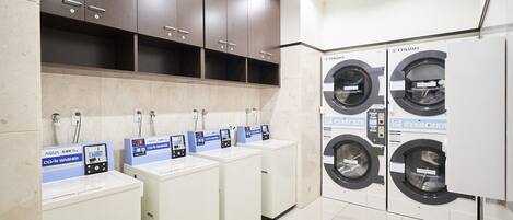 A laundry facility with four washing machines and three sinks with coin-operated washers.