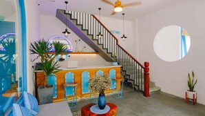A modern interior with a staircase, a reception desk, and a round mirror. - To Vo Hue Hostel (Hue)