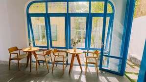 A room with a large window, a round table, and four chairs. - To Vo Hue Hostel (Hue)