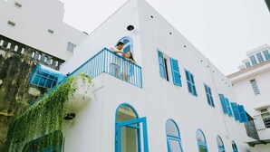 A white building with blue shutters and a balcony. - To Vo Hue Hostel (Hue)