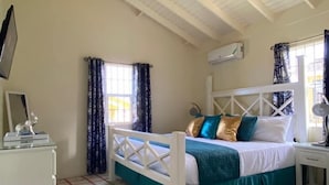 Un dormitorio con cama, ventilador de techo, ventana con cortinas, mesita de noche y aire acondicionado instalado en la pared.