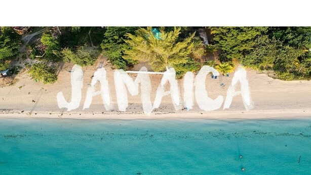 Una playa con la palabra "JAMAICA" escrita en la arena.