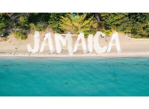 A beach with the word "JAMAICA" painted on the sand. - Oasis At The Manor (Florence Hall)