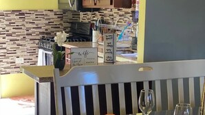 Un comedor con una mesa para dos, una banca y una cocina al fondo.