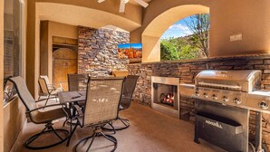 An outdoor patio with a stone wall, a grill, and a dining area with chairs and a table. - B6, Hillside Hideaway, Indoor and Outdoor Fireplace, Community Amenities, Near Sand Hollow (Hurricane)