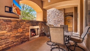 A stone fireplace with a fire, a ceiling fan, and a stone wall. - B6, Hillside Hideaway, Indoor and Outdoor Fireplace, Community Amenities, Near Sand Hollow (Hurricane)
