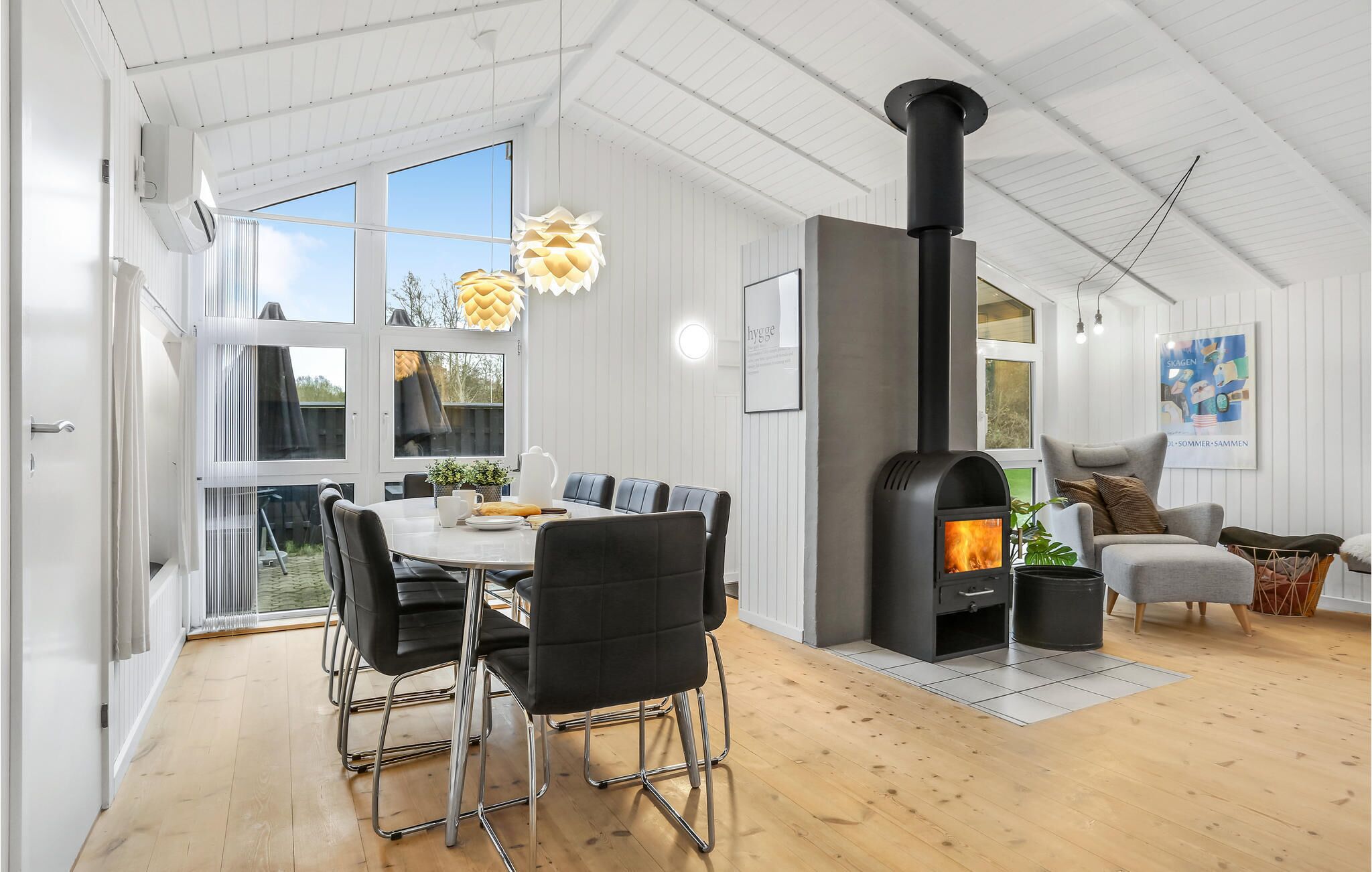 En modern inredning med ett matområde, en öppen spis och en mysig sittgrupp.