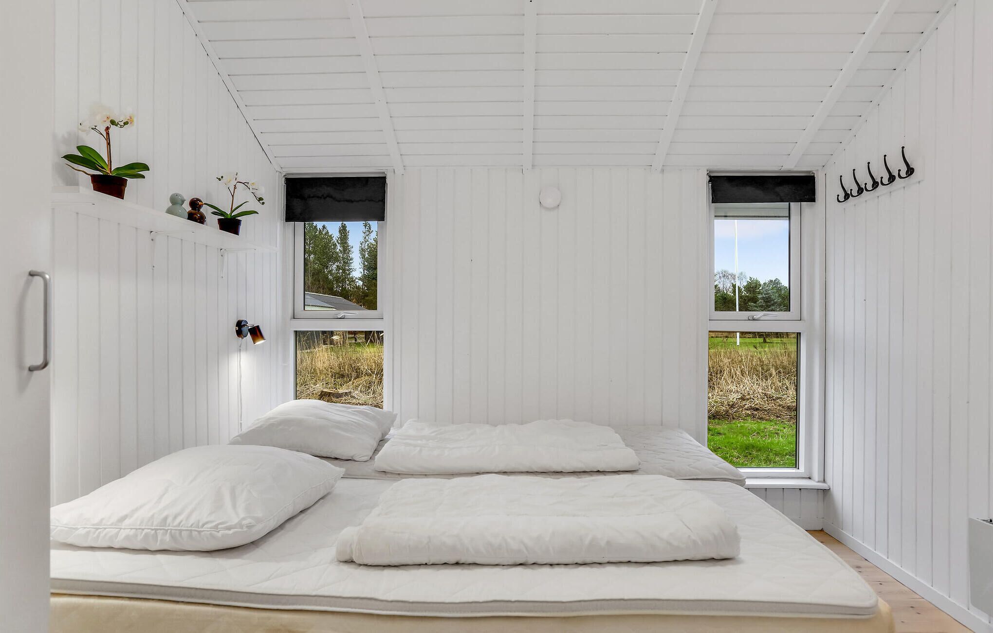 A room with a bed, two windows, and a view of the outdoors.