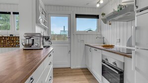 Eine moderne Küche mit weißen Schränken, einer Holzarbeitsplatte, einer Kaffeemaschine und einem Backofen.